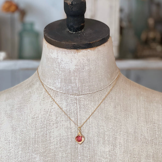 A gold Calla Lily ruby necklace displayed on a vintage-style mannequin torso, showing the elegant length and fit.