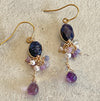 Handmade wire wrapped earrings with dark blue sapphire and purple amethyst drops on vintage background