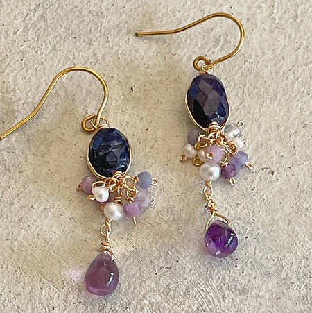 Handmade wire wrapped earrings with dark blue sapphire and purple amethyst drops on vintage background