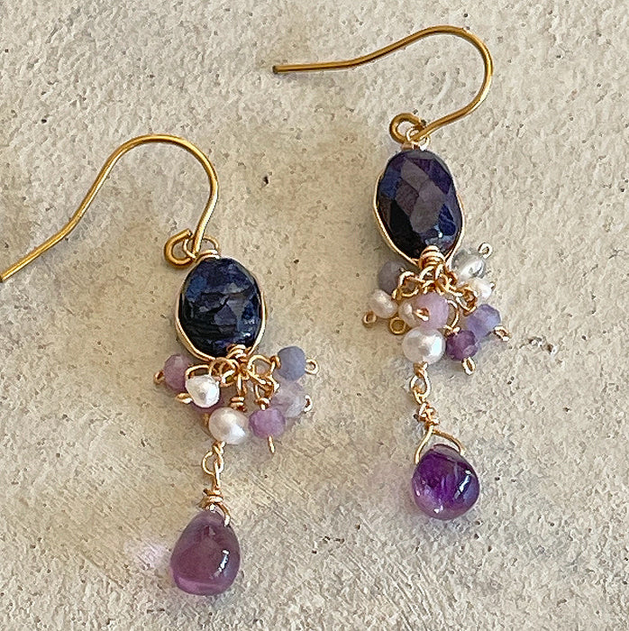 Handmade wire wrapped earrings with dark blue sapphire and purple amethyst drops on vintage background