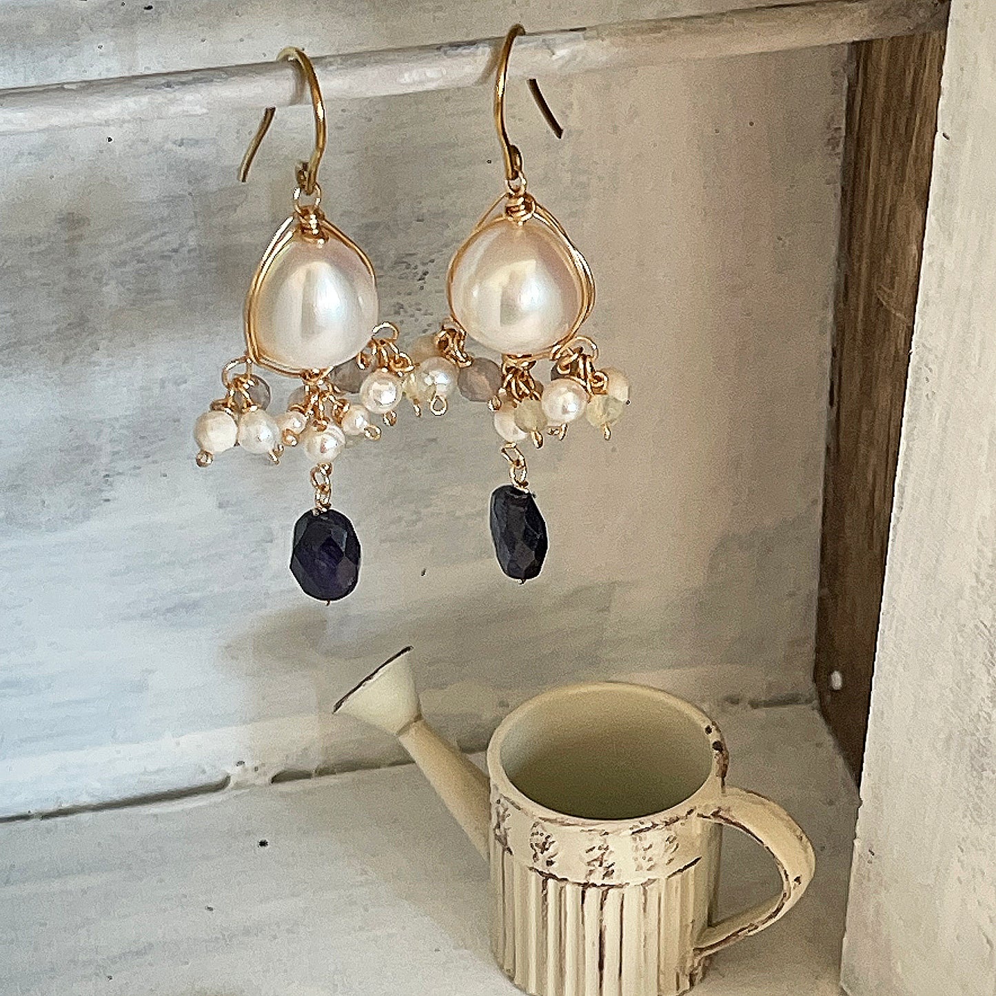 Gorgeous baroque pearl and blue sapphire chandelier earrings hanging in a handmade miniature vintage armoire 